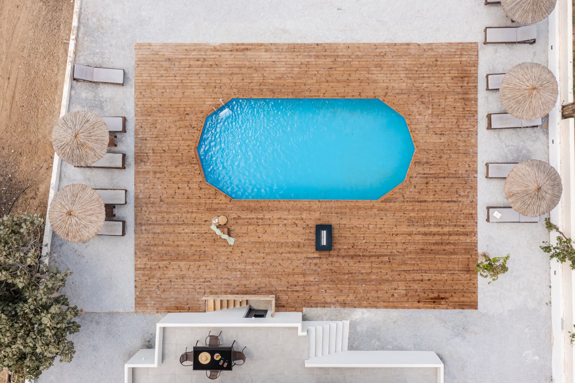 Αεροφωτογραφία της πισίνας της Villa Eira με ξύλινο κατάστρωμα και ψάθινες ομπρέλες